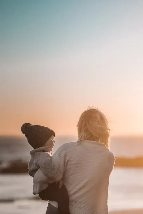 Woman with a kid on her hip looking at the horizon